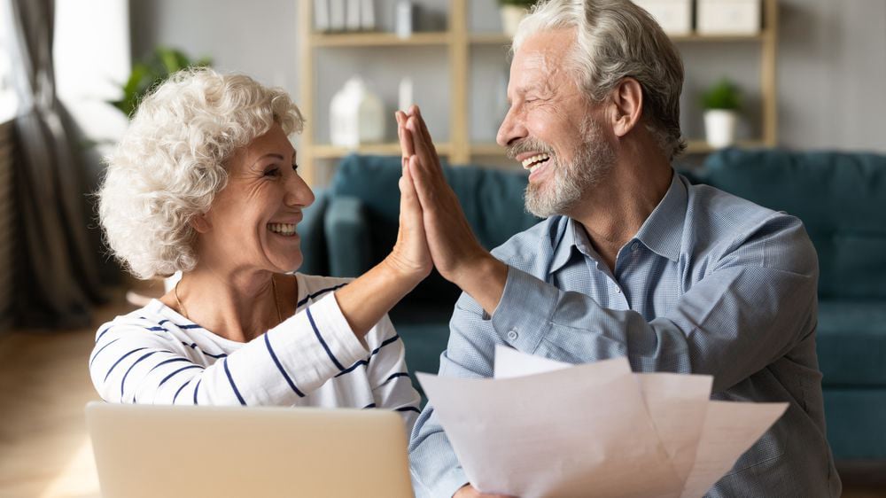 Pareja de jubilados feliz celebrando su préstamo